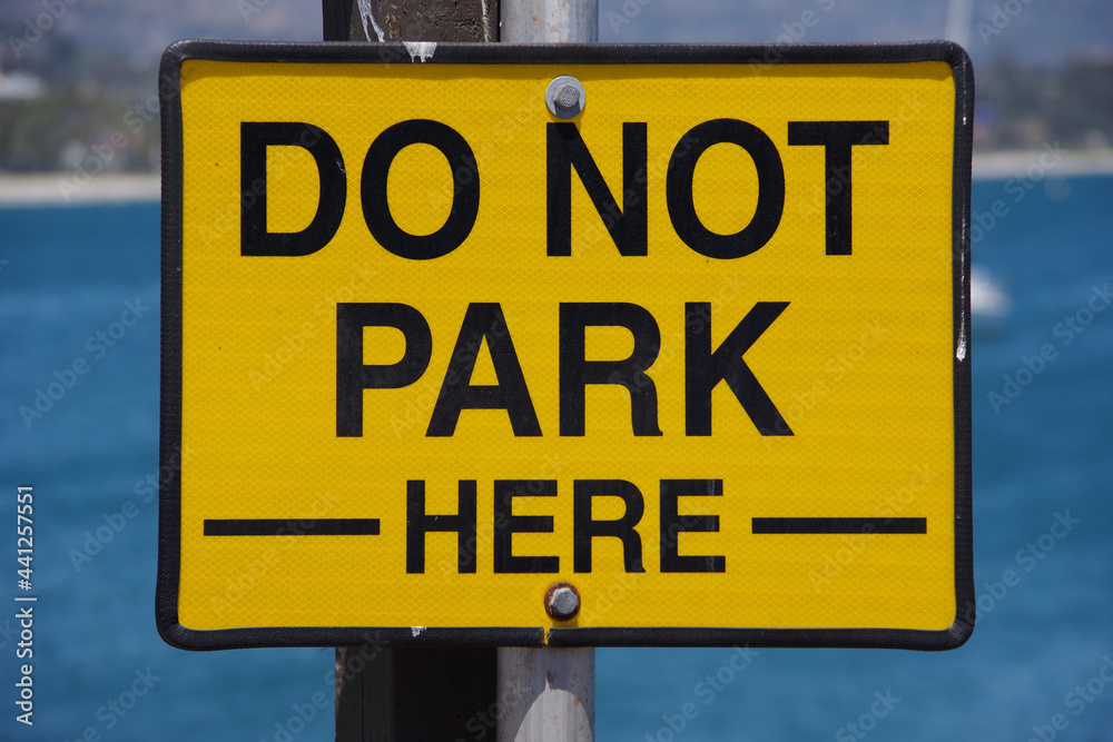 Large yellow and black sign on a pacific ocean wharf in California