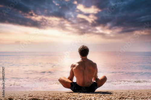 Man meditates on the sandy beach view from the back
