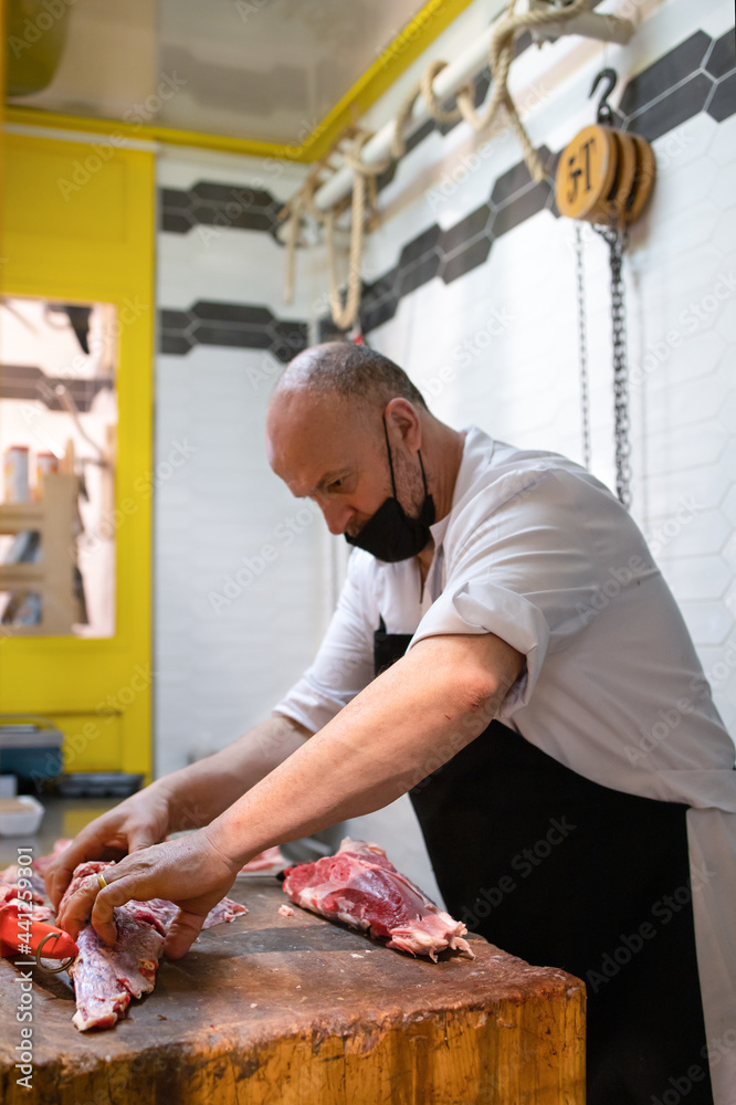 Butcher cuts up a piece of fresh farm meat in his store