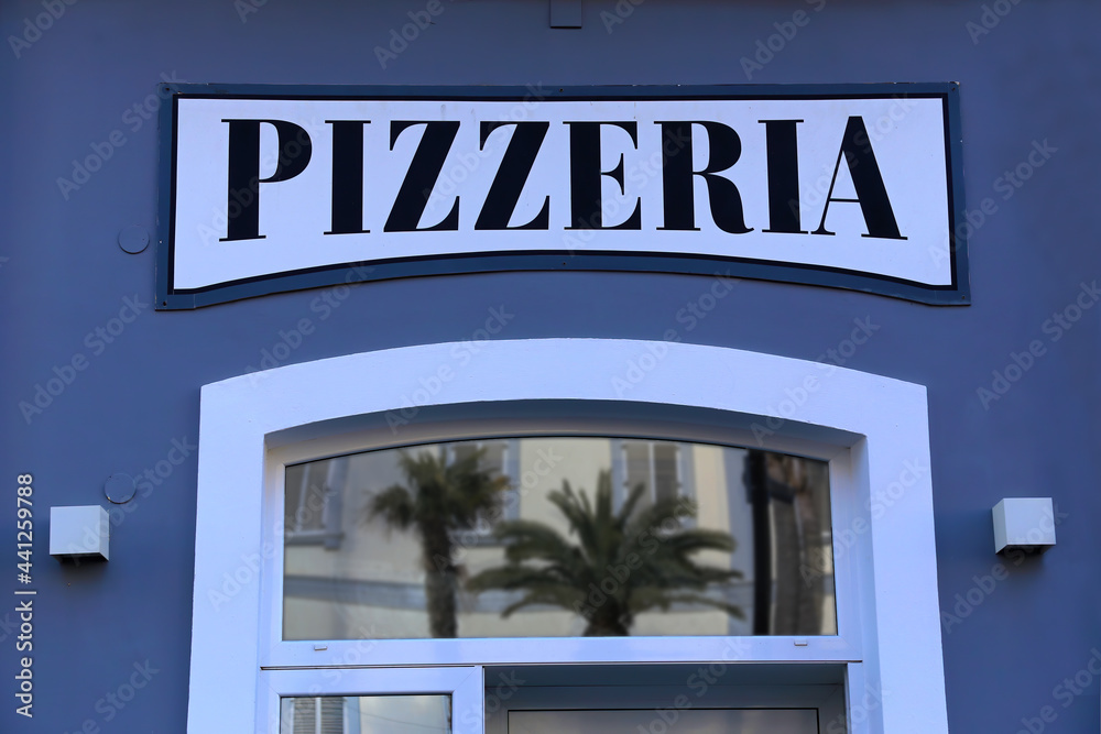 Pizza restaurant sign above the entrance door against a blue facade Pizza restaurant sign above the entrance door against a blue facade