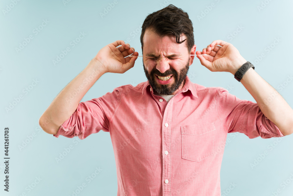 Fototapeta premium Attractive man feeling pain while cleaning his ears