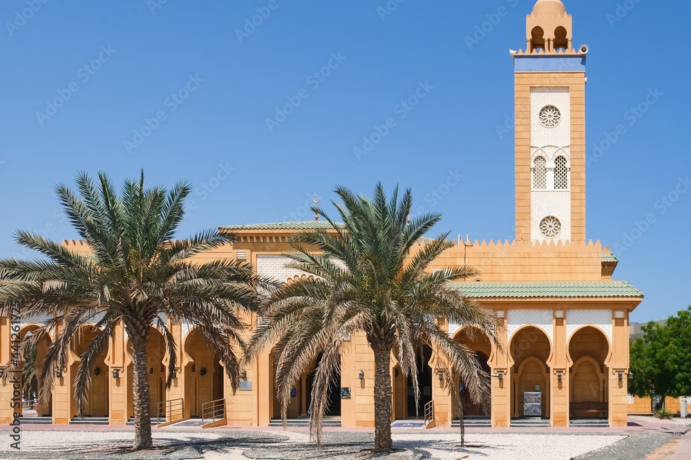 View to urban Mosque in typical moroccan style wit h majestic minaret and archways gallery, covered  white arabesque mosaic tiles located in Abu Dhabi,UAE