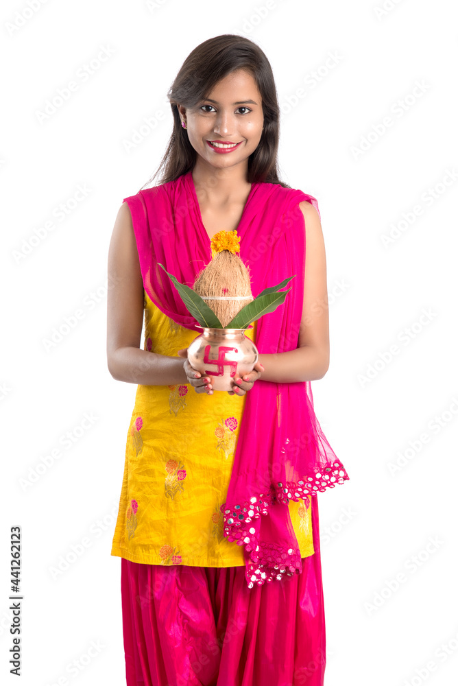 Indian girl holding a traditional copper Kalash, Indian Festival, copper Kalash with coconut and mango leaf with floral decoration, essential in Hindu Pooja. Indian girl holding a traditional copper Kalash, Indian Festival, copper Kalash with coconut and mango leaf with floral decoration, essential in Hindu Pooja.