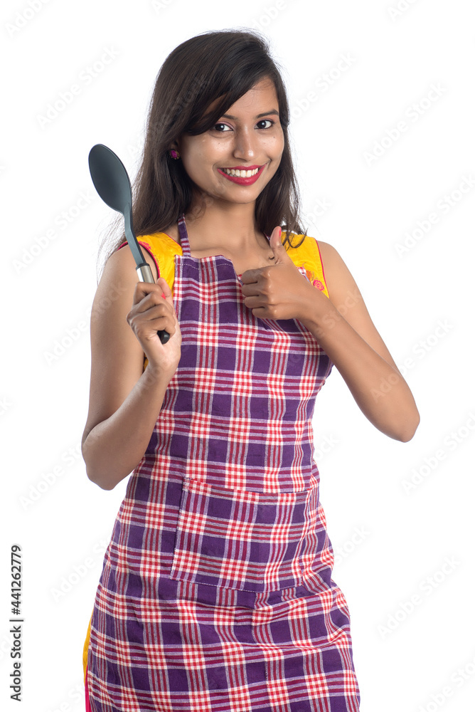Young Indian woman holding kitchen utensil (spoon, stapula, ladle, and pan, etc.) on a white background Young Indian woman holding kitchen utensil (spoon, stapula, ladle, and pan, etc.) on a white background