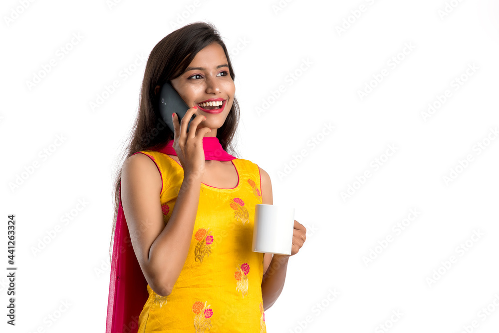 Pretty young girl calling on smartphone device while drinking tasty coffee or tea beverage Pretty young girl calling on smartphone device while drinking tasty coffee or tea beverage