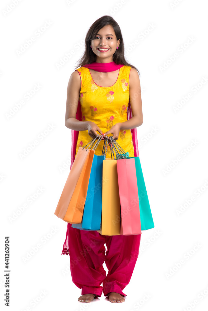 Beautiful Indian young girl holding and posing with shopping bags on a white background Beautiful Indian young girl holding and posing with shopping bags on a white background