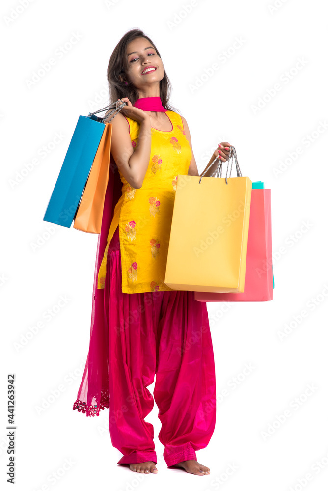Beautiful Indian young girl holding and posing with shopping bags on a white background Beautiful Indian young girl holding and posing with shopping bags on a white background