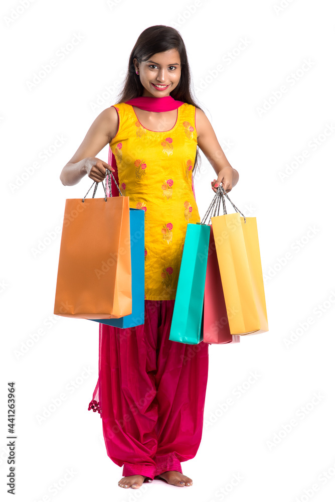 Beautiful Indian young girl holding and posing with shopping bags on a white background Beautiful Indian young girl holding and posing with shopping bags on a white background