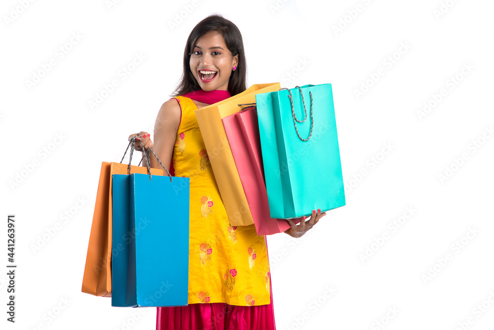 Beautiful Indian young girl holding and posing with shopping bags on a white background Beautiful Indian young girl holding and posing with shopping bags on a white background