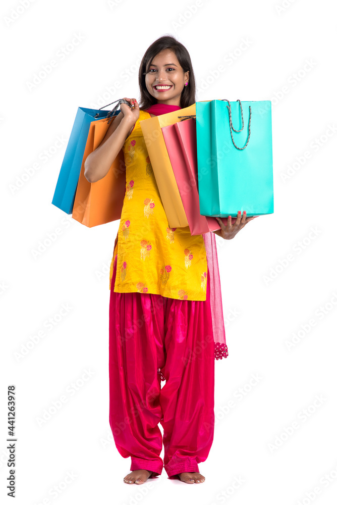 Beautiful Indian young girl holding and posing with shopping bags on a white background Beautiful Indian young girl holding and posing with shopping bags on a white background