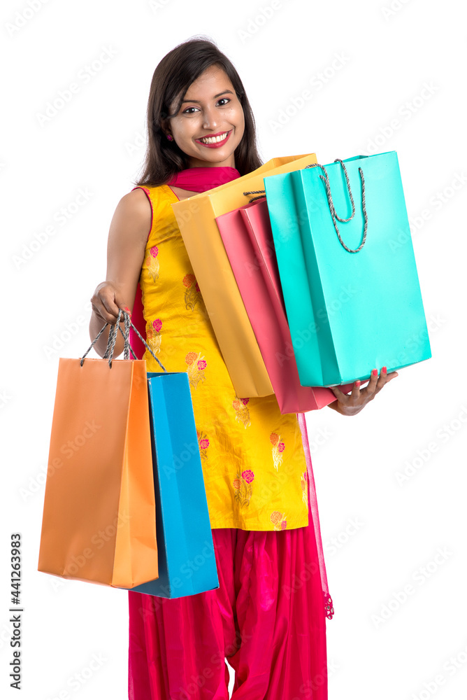 Beautiful Indian young girl holding and posing with shopping bags on a white background Beautiful Indian young girl holding and posing with shopping bags on a white background