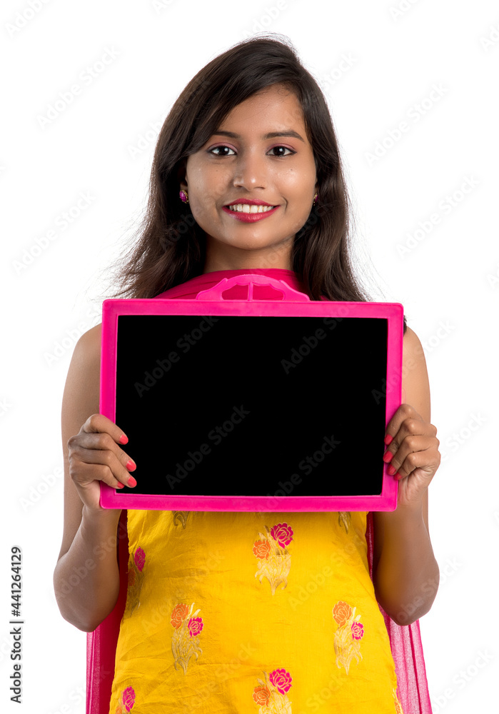 Beautiful young girl holding and showing something on a chalkboard or slate, isolated over white background Beautiful young girl holding and showing something on a chalkboard or slate, isolated over white background