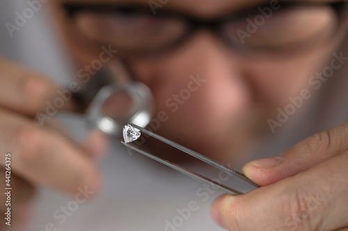 Close up of diamond dealer s hands evaluating diamond at international jewelry exhibition. High quality photo