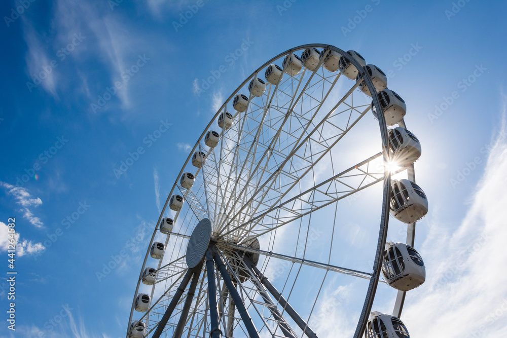 Ferris wheel against the blue sky and clouds on a sunny day - Saint Petersburg, Russia 2021