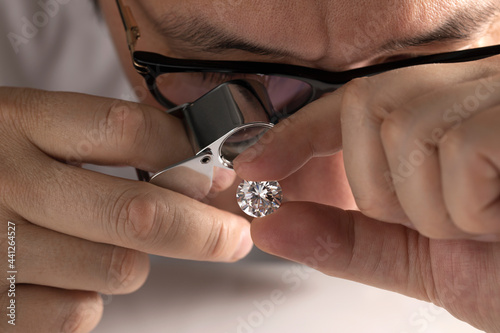 Bild auf Leinwand Close up of diamond dealer's hands evaluating diamond at international jewelry exhibition