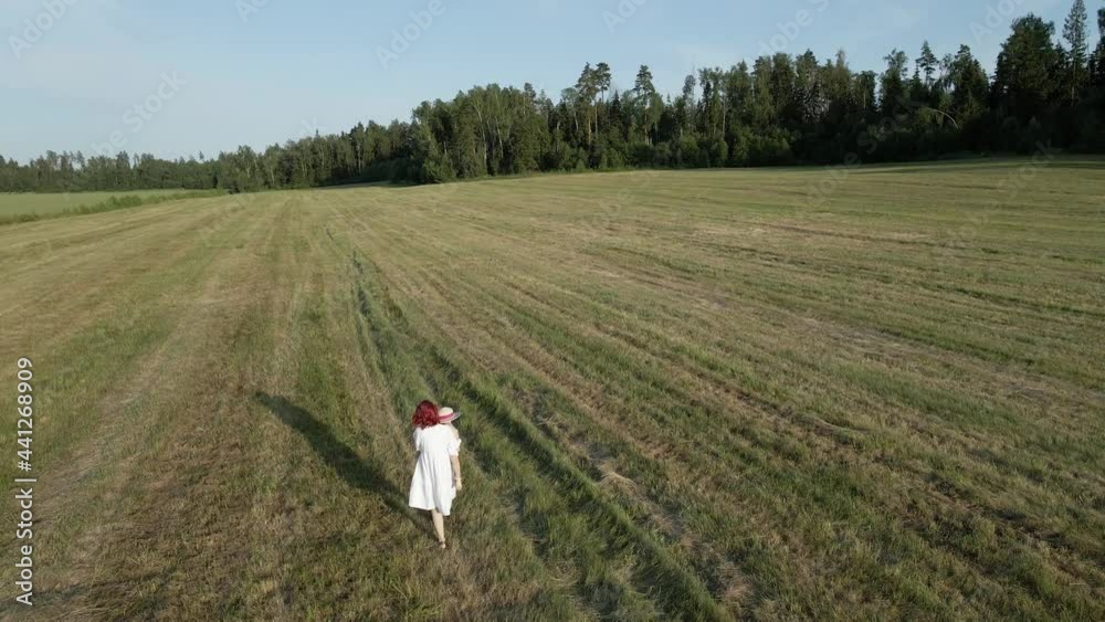 mom in white dresses with her daughter walking on a mown field in the summer mom in white dresses with her daughter walking on a mown field in the summer