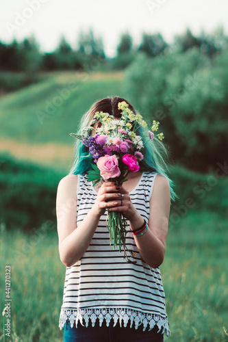 girl covering her face behind a bouquet of freshly picked flowers