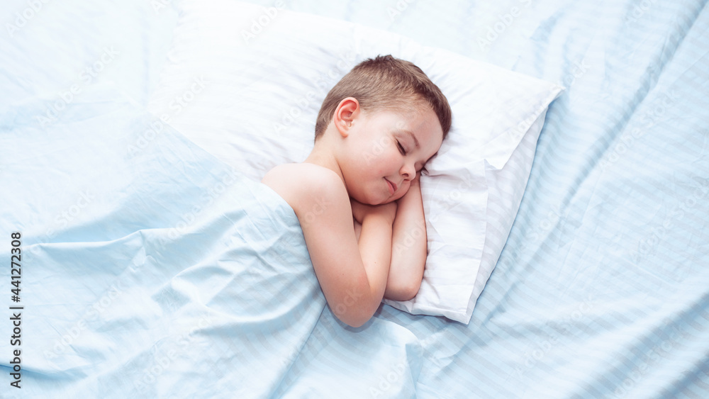 Cute four five year old toddler boy sleeping calm on fresh blue bedding with white pillow. Cute four five year old toddler boy sleeping calm on fresh blue bedding with white pillow.