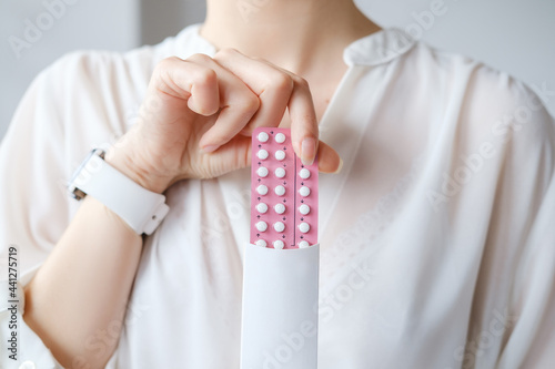 Papier peint Unrecognized woman in white blouse holding hormonal oral contraceptives in a pink blister