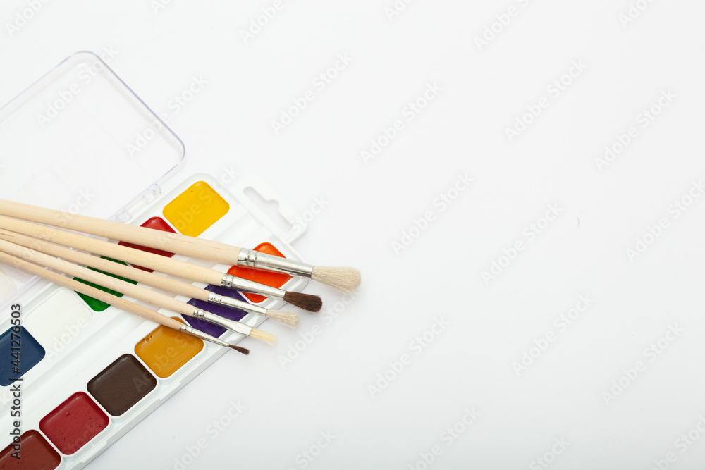 A set of watercolor paints and paint brushes on a white background with a copy space for text A set of watercolor paints and paint brushes on a white background with a copy space for text