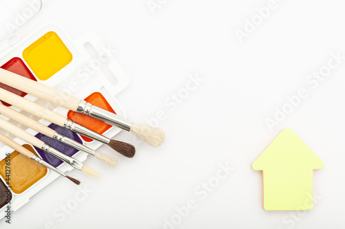 Paint palette with tassels and house stickers on a white background