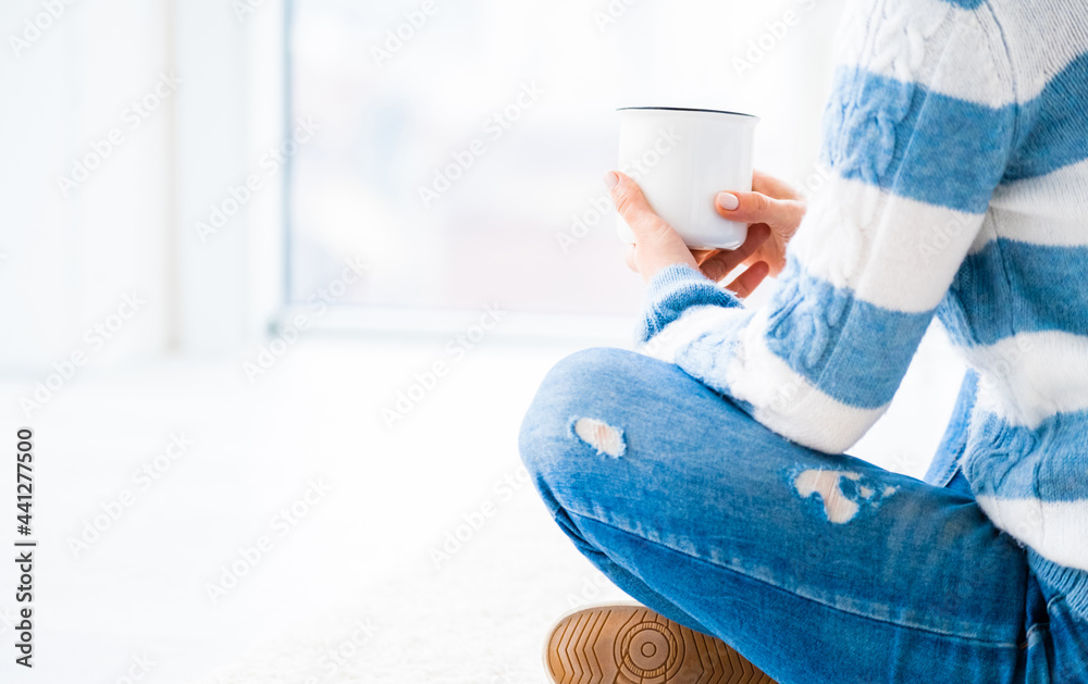 Fototapeta premium Girl relaxing near window with cup of tea indoors