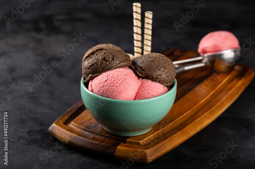 Bowl with Neapolitan ice cream on dark background. photo