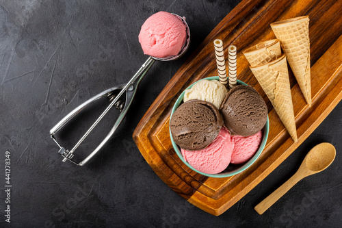 Bowl with Neapolitan ice cream on dark background. photo