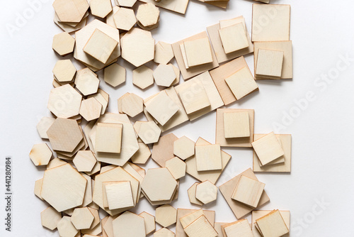 various hexagonal and square wooden shapes piled and layered randomly on white