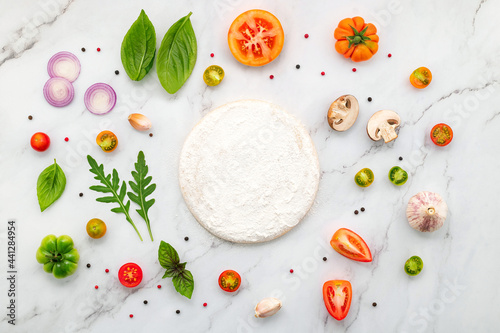 The ingredients for homemade pizza set up on white marble background with copy space and top view.