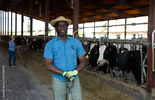 Portrait of a hardworking african american man standing on a livestock farm with a working tool in his hand