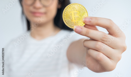 Fototapeta Naklejka Na Ścianę i Meble -  Woman holding a Bitcoin token. Cryptocurrency is a virtual or digital money which takes the form of tokens or “coins” it can be used to buy goods and services.