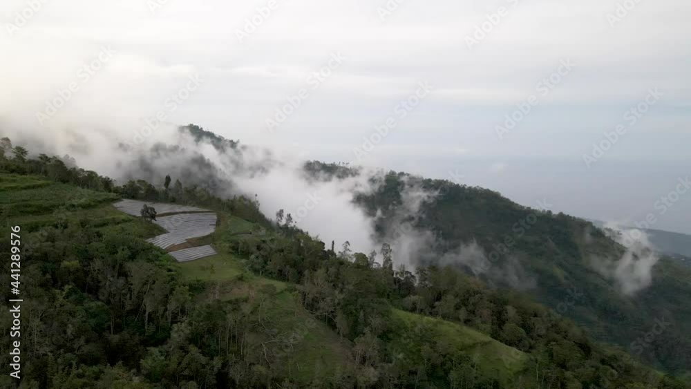 Flying over majestic Bali landscape covered in fog.