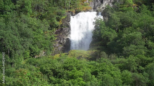 One of the many beautiful waterfalls of the Naeroyfjord, hidden in the forest-covered mountainside. The mighty flow of whitewater cascading from the dark cliffs, splashing and raising water spray. photo