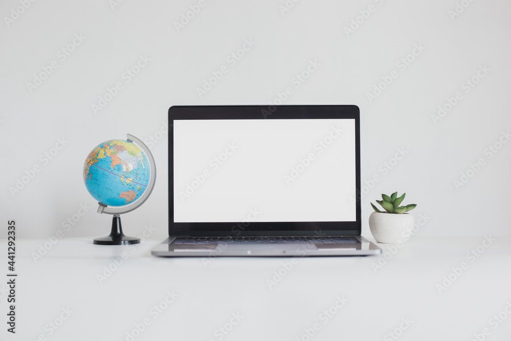 Fototapeta premium Blank screen laptop between mini globe and succulent isolated on white background