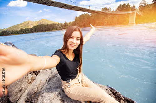 Happy travel blogger young woman make selfie photo trip in Russia, background blue river Katun Altay © Parilov
