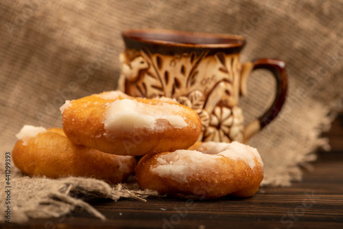 Fresh homemade doughnuts with powdered sugar and a earthenware mug of tea. Close-up Selective focus. photo