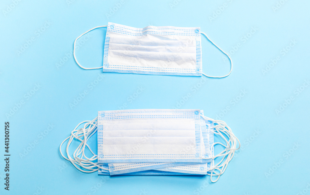 Dirty used mask and stack of clean new medical masks on a blue background. Dirty used mask and stack of clean new medical masks on a blue background.