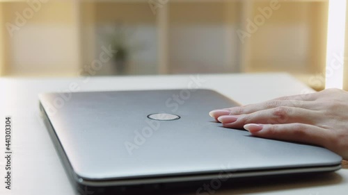 Finish work. Female freelance worker. Computer device. Remote job. Unrecognizable woman closing laptop cover in light room interior. photo