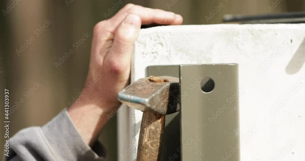 Man Hammering A Screw Into The Bracket On The Wall. - close up Man Hammering A Screw Into The Bracket On The Wall. - close up