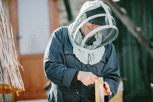 Senior man beekeper collecting honey from honeycomb photo