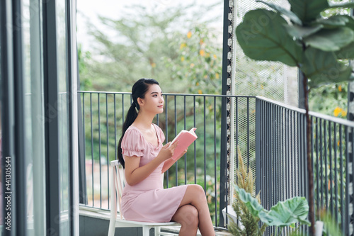Young woman reads a book at balcony