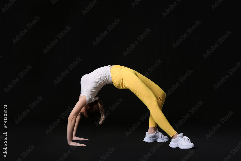 Sporty young woman training against dark background
