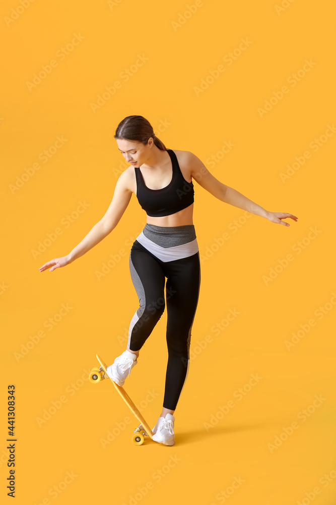 Sporty young woman with skateboard on color background