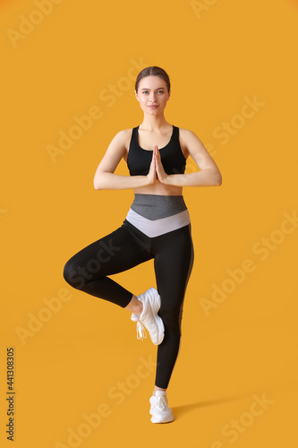 Sporty young woman doing yoga on color background