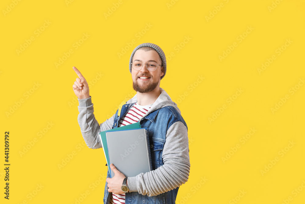 Male student pointing at something on color background