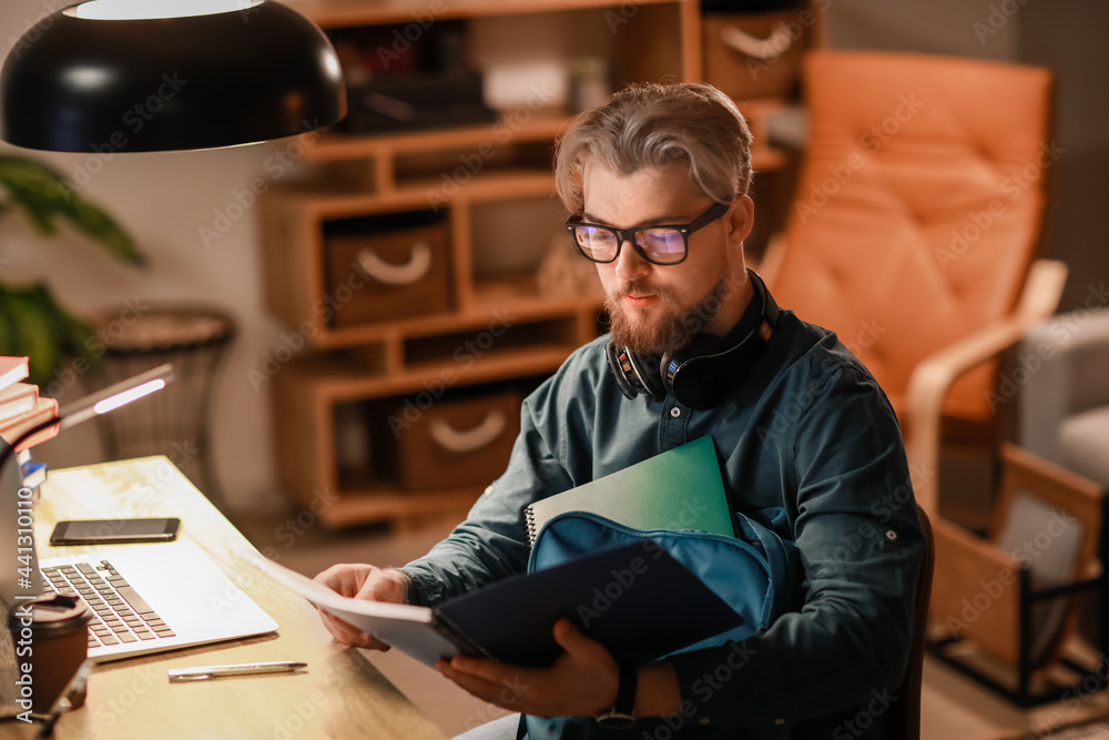 Young man studying online at home in evening Young man studying online at home in evening