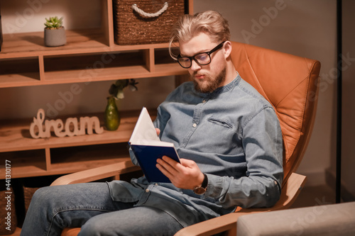 Young man reading book whil...