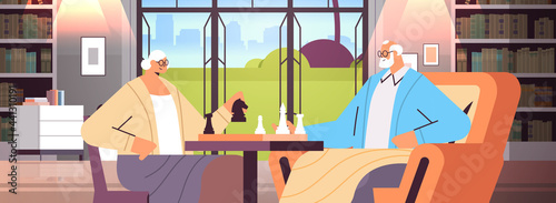 elderly couple playing chess senior man woman spending time together living room interior horizontal