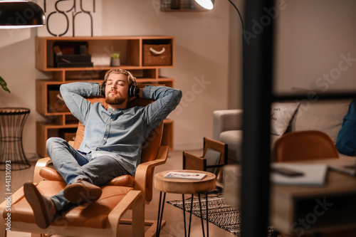 Young man listening to music while sitting in armchair at home